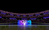 A futuristic football stadium glowing with neon lights under a night sky.