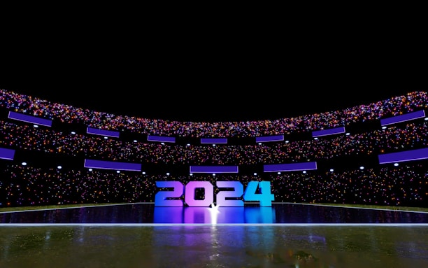 A futuristic stadium illuminated with vibrant lights displays the numbers 2024 prominently at its center. The stadium is filled with colorful lights and reflective surfaces, creating a dynamic and festive atmosphere.