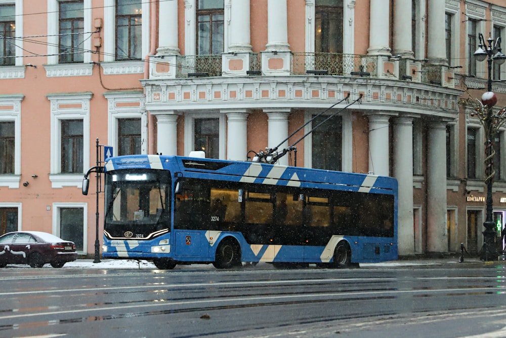 a blue bus driving down a street next to tall buildings