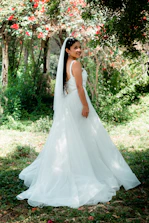 A bride in Victorian-inspired attire posing gracefully in a sunlit garden.