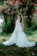 Bride smiling happily in a custom-made wedding dress, standing in a sunlit garden.