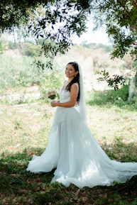 A candid shot of a bride laughing during a photo shoot, surrounded by natural greenery.