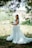 A happy bride wearing a flowing wedding dress from allinresales, smiling outdoors.