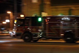 A tow truck speeding through a city street at dusk with flashing lights.