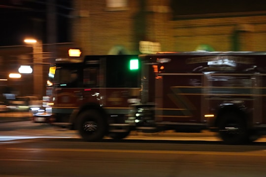 A tow truck speeding through a city street at dusk with flashing lights.