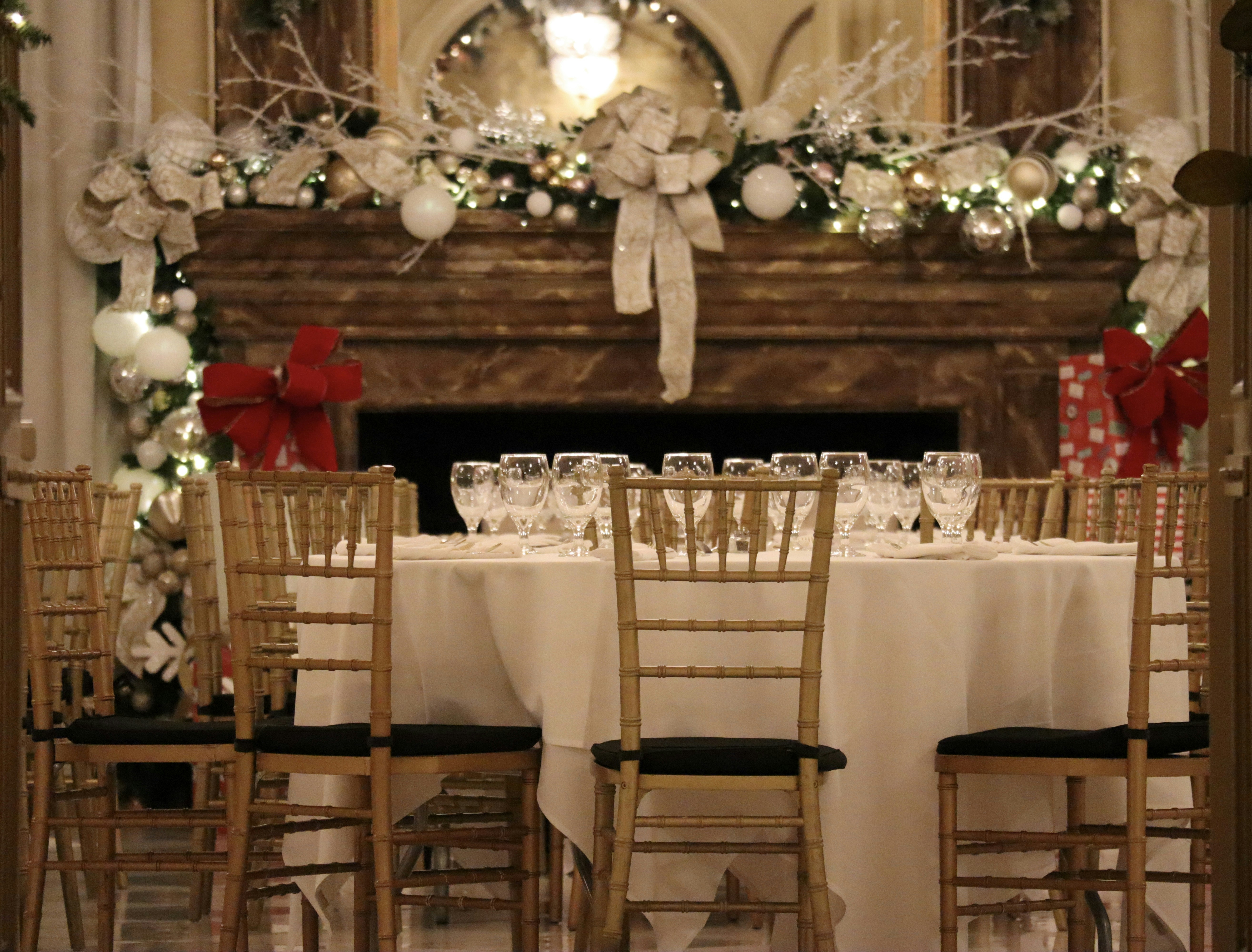 a table set for a formal dinner with a fireplace in the background