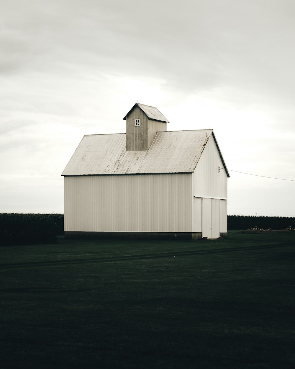 a large white barn sitting on top of a lush green field