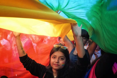 Close-up of smiling friends sharing a moment with rainbow flags waving gently.