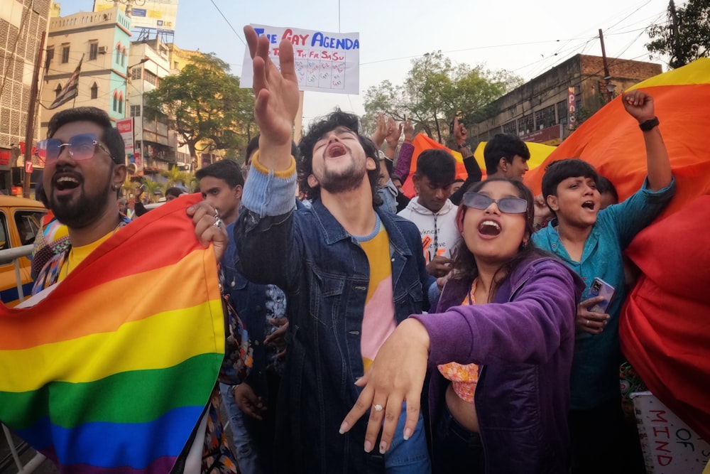 a group of people standing around each other holding a rainbow flag