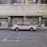 A taxi parked near a vibrant Madrid café with colorful street art in the background.