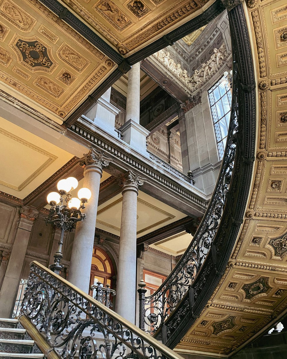 a spiral stair case in a building with a chandelier