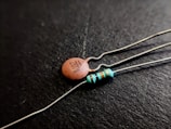 Close-up shot of two electronic components on a black background; one is a ceramic capacitor with '103Z' printed on it, and the other is a resistor with colored bands.
