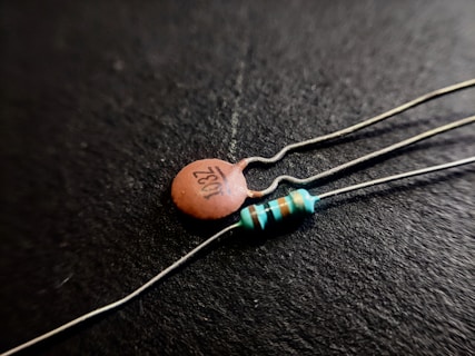Close-up shot of two electronic components on a black background; one is a ceramic capacitor with '103Z' printed on it, and the other is a resistor with colored bands.