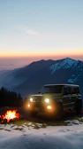 A Rivian R1T towing a 26ft camper parked at a scenic mountain overlook during sunset.