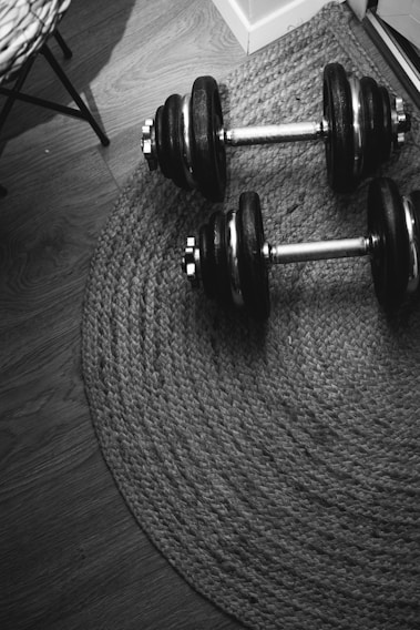 A close-up shot of adjustable dumbbells resting on a sleek wooden floor with natural light highlighting their design.