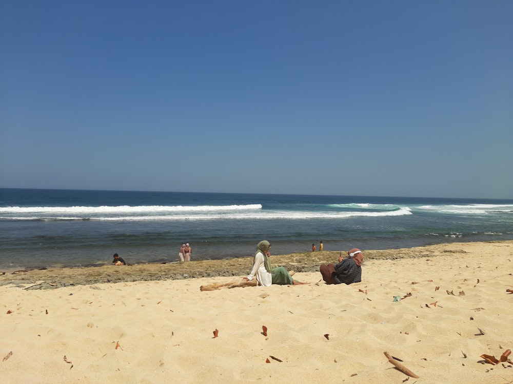 a group of people sitting on top of a sandy beach