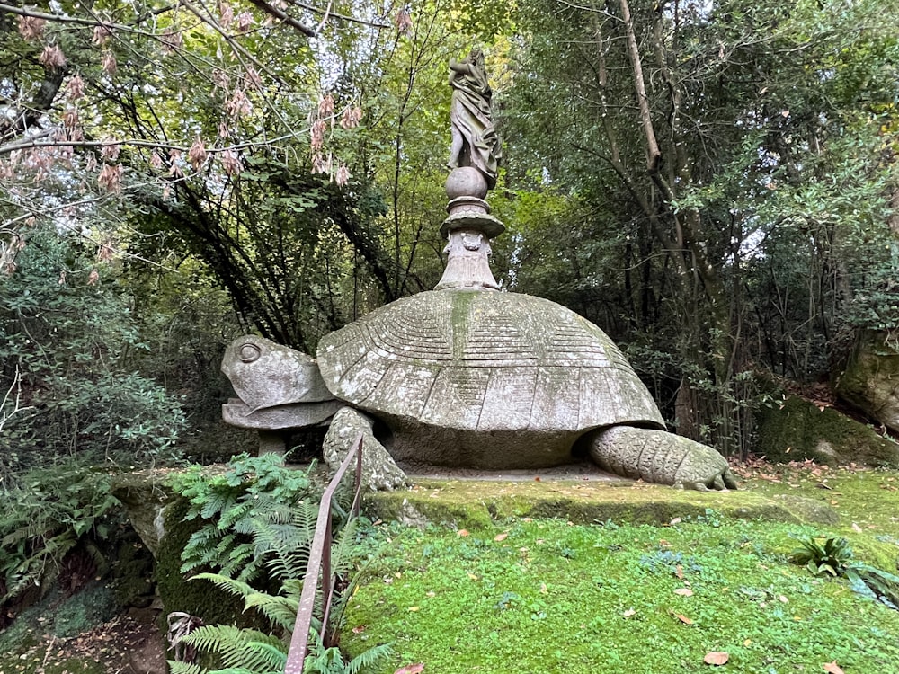 a statue of a turtle sitting on top of a lush green field