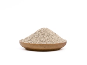 A wooden bowl filled with a mound of small, beige grains rests against a plain white background.
