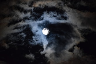 a full moon is seen through the clouds