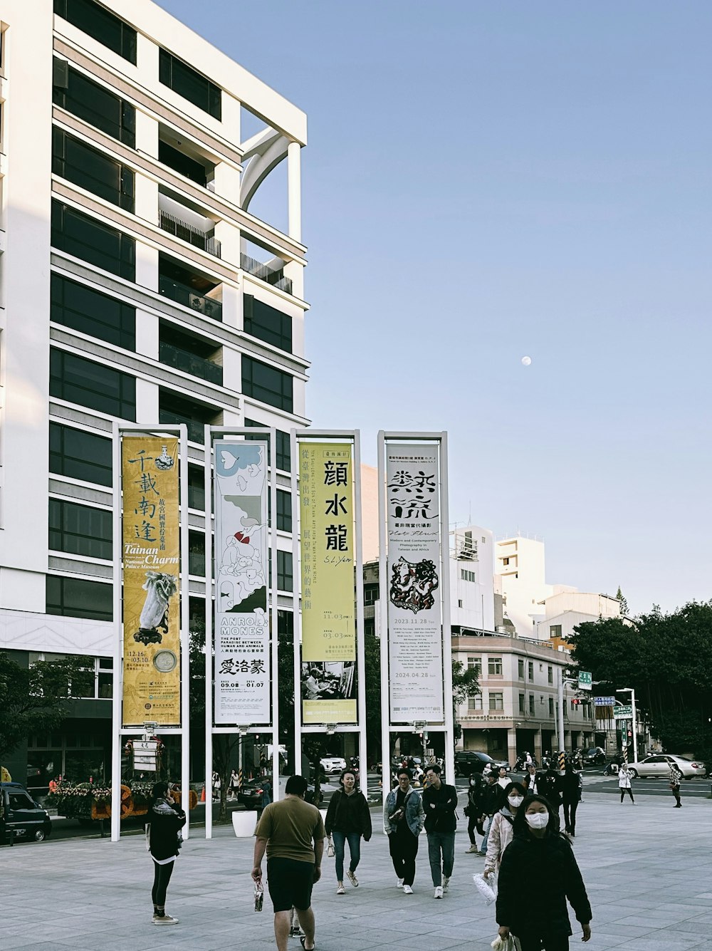 a group of people walking down a street next to tall buildings