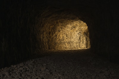 A dimly lit tunnel with makeshift bedding and personal belongings scattered around.