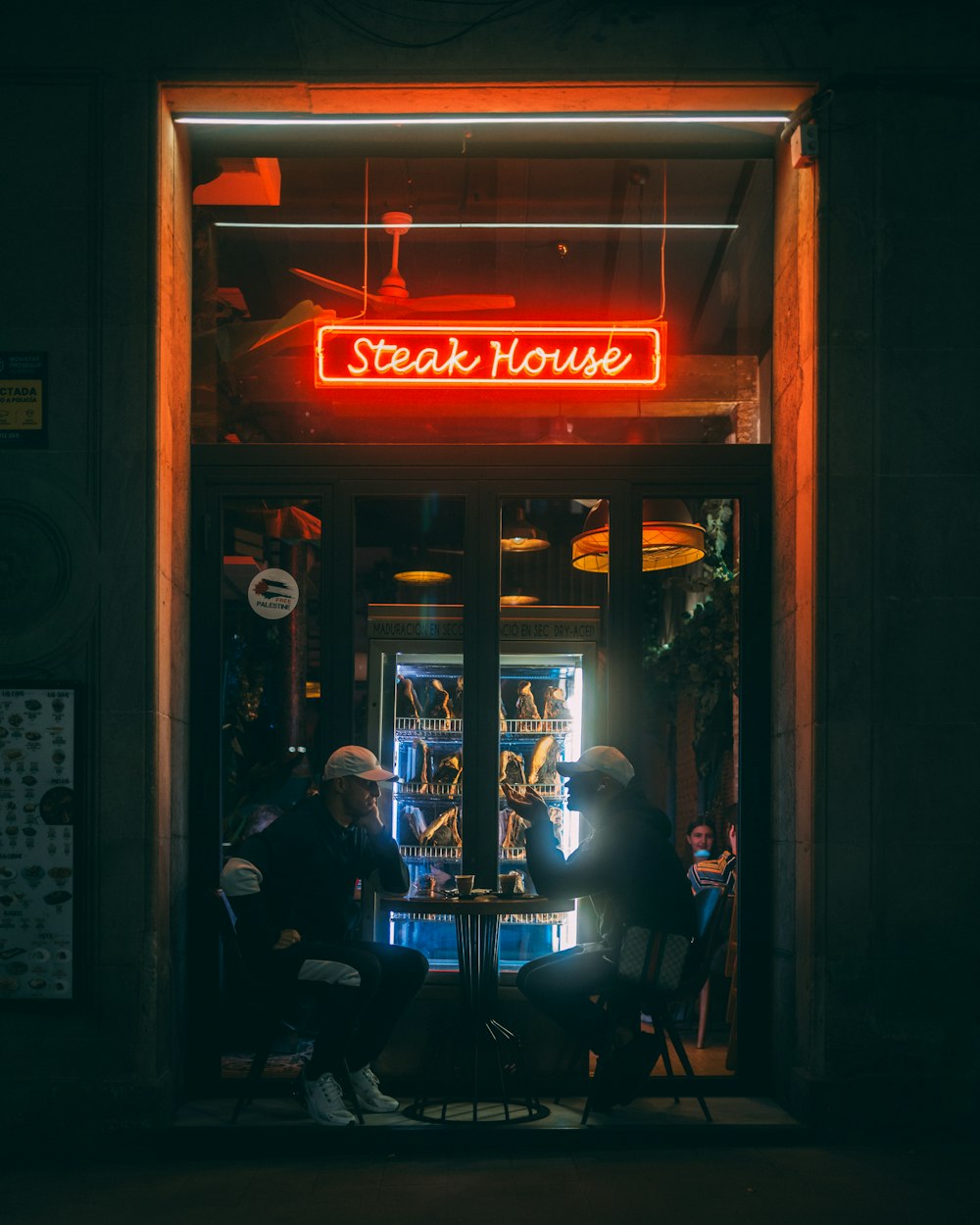 two people sitting at a table in front of a restaurant