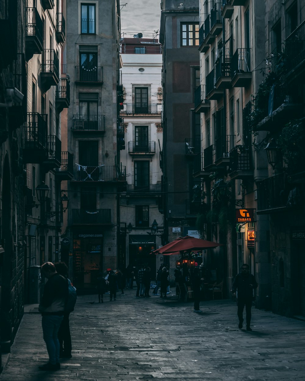 a group of people walking down a street next to tall buildings