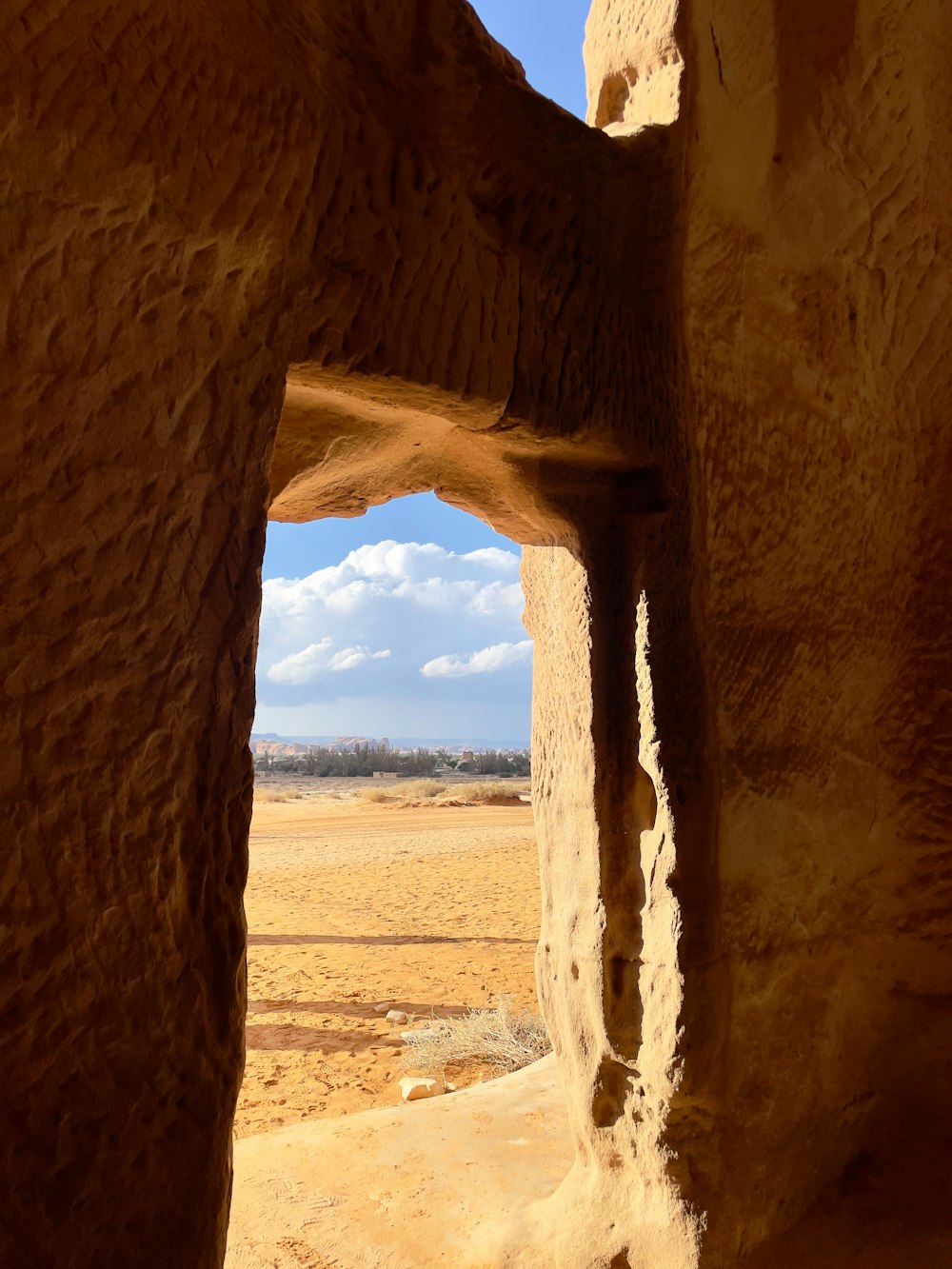 a view of a desert through a small opening in a rock wall