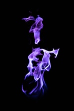 An abstract purple and black visual blending smoke and light to evoke mystery.