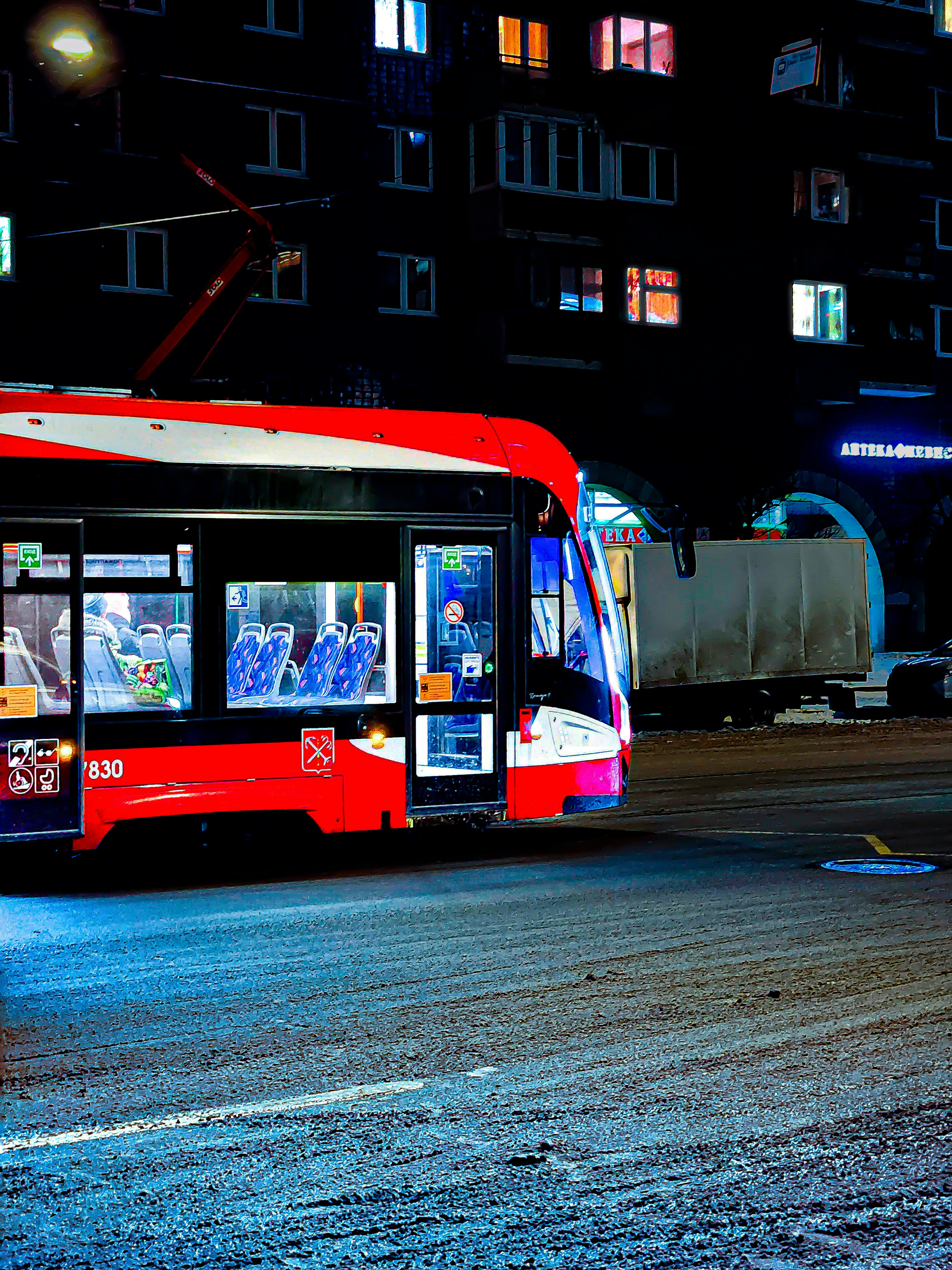 a red bus driving down a street at night