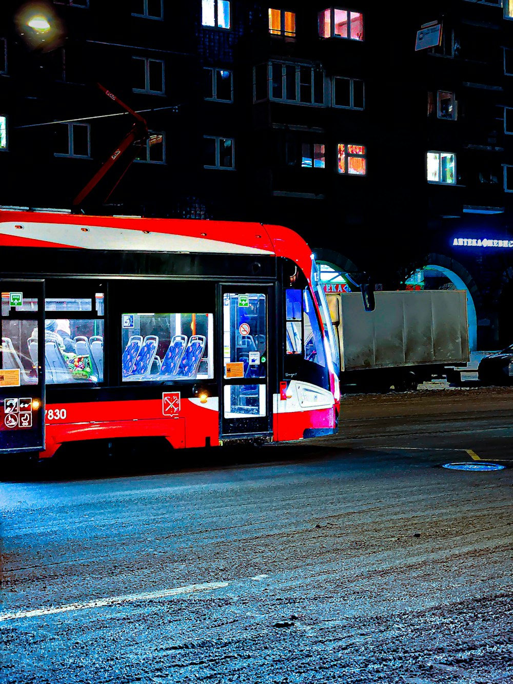 a red bus driving down a street at night