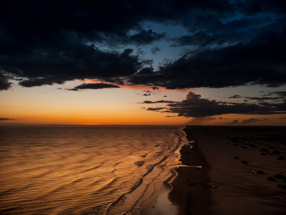 the sun is setting over the ocean on the beach