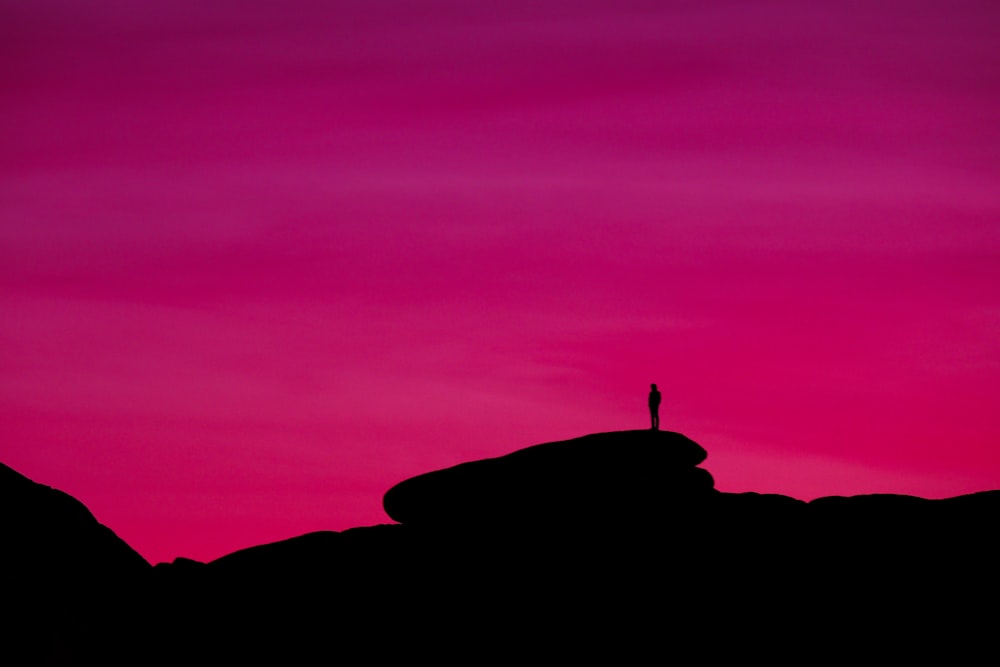 a person standing on top of a hill at sunset