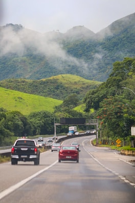 a group of cars driving down a road with mountains in the background