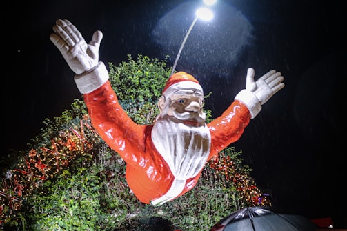 Santa Claus waving from the brightly decorated sleigh as it moves through a snowy Watford street at dusk.