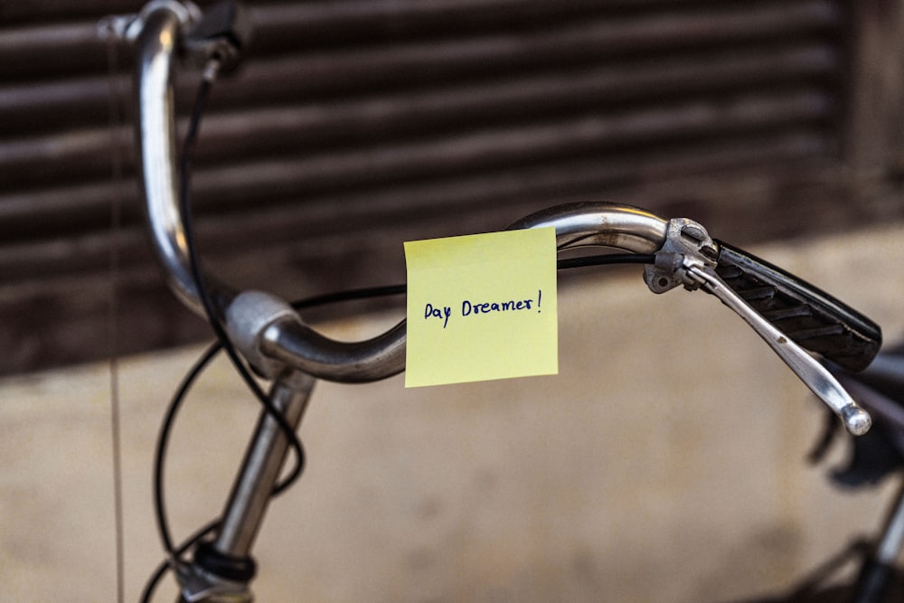 a close up of a bicycle with a sticky note attached to the handlebars