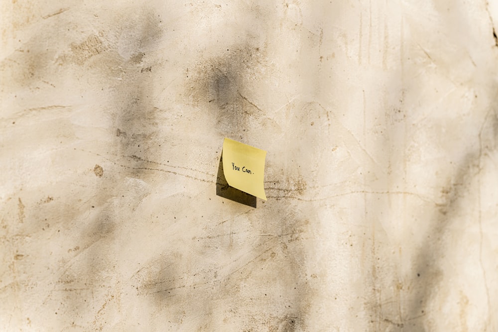 a piece of yellow paper stuck to the side of a wall