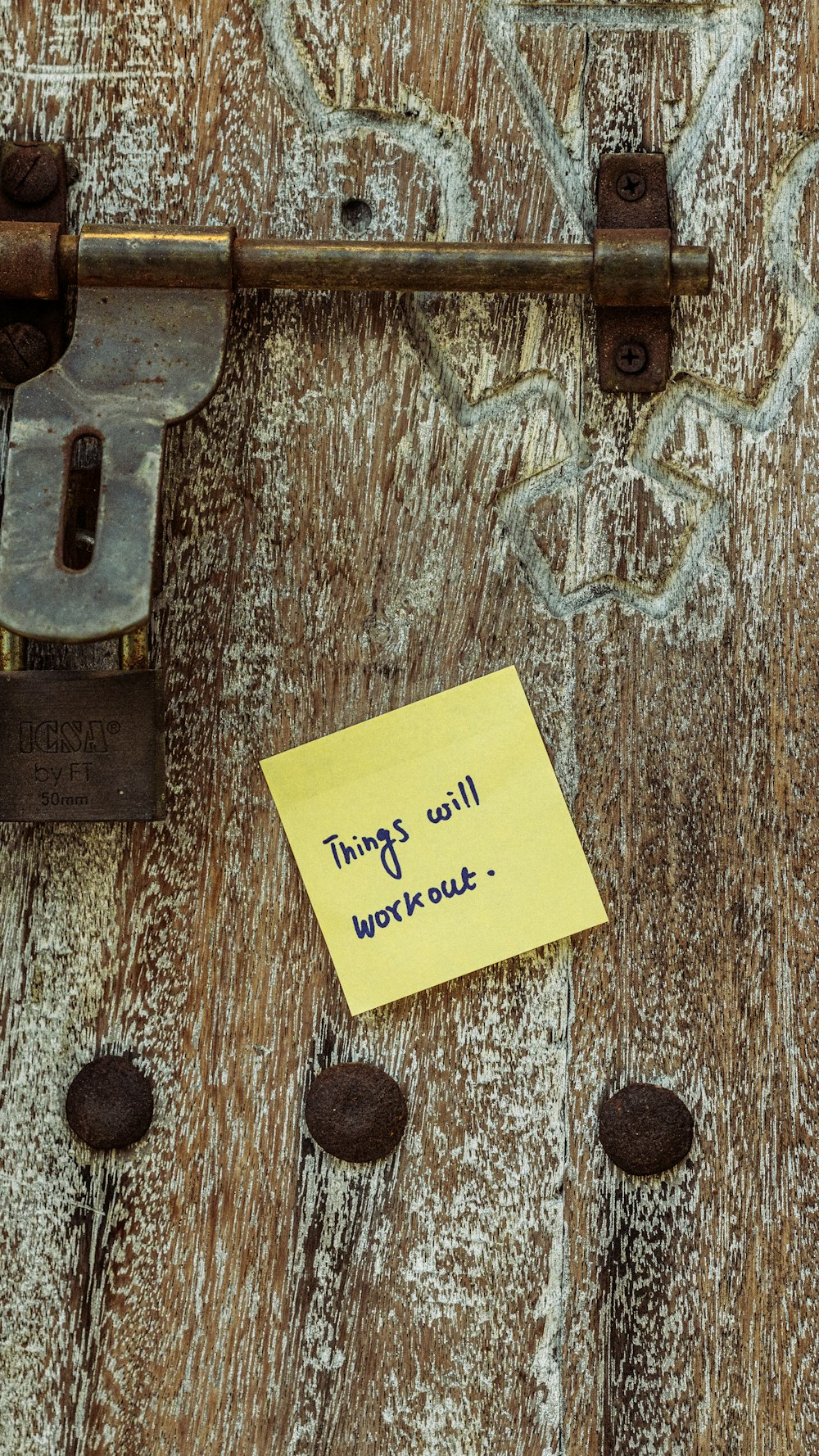 a piece of yellow paper sitting on top of a wooden door