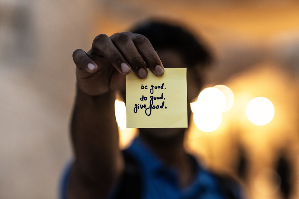 a person holding a piece of paper with writing on it