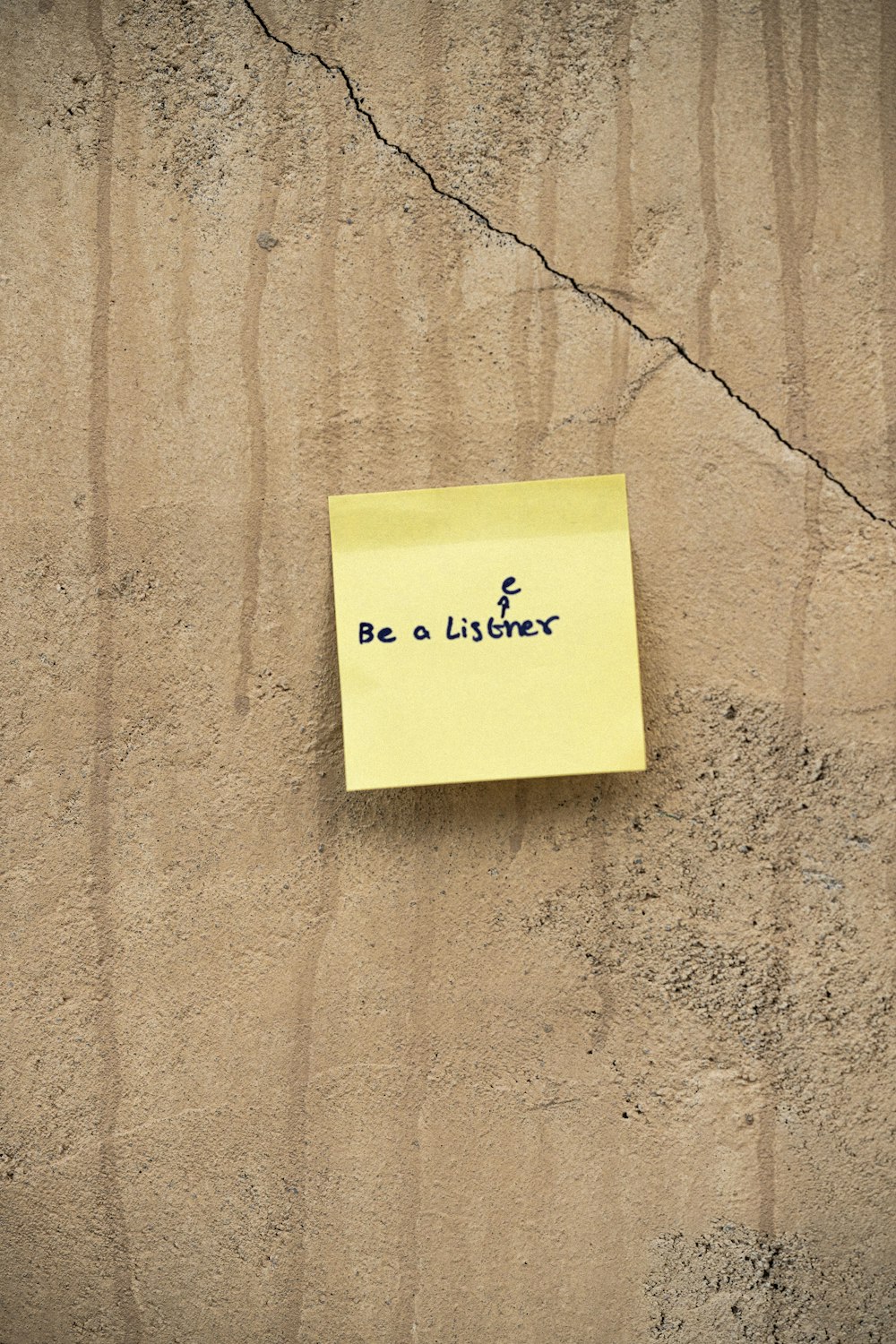 a yellow post it note attached to a concrete wall