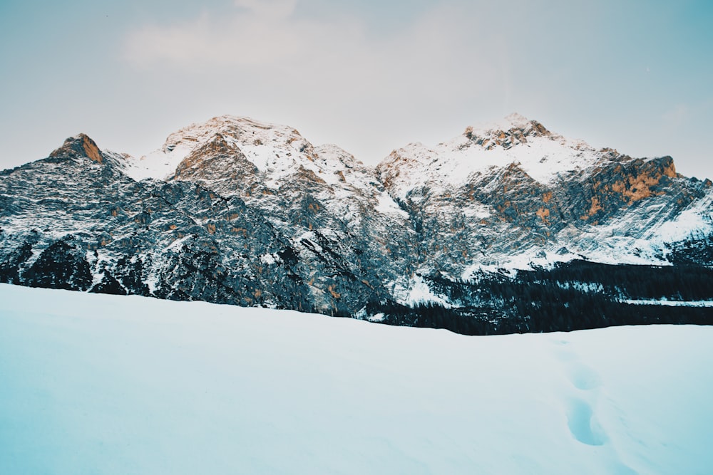 a snow covered mountain range with tracks in the snow