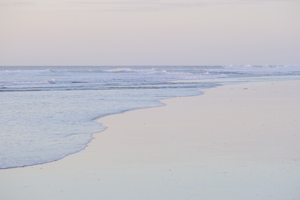 a person walking on the beach with a surfboard