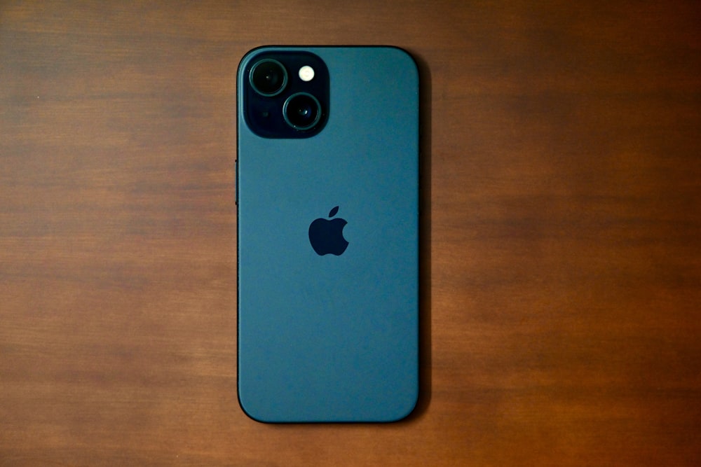 Un iPhone azul sentado encima de una mesa de madera