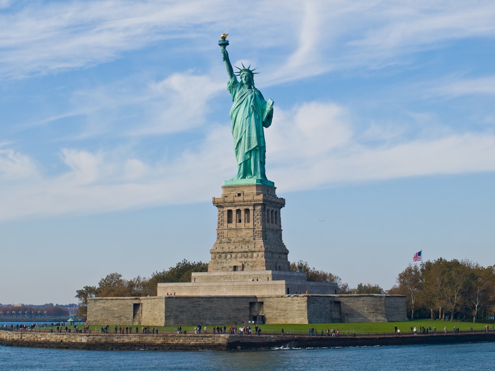 the statue of liberty stands in the middle of a body of water