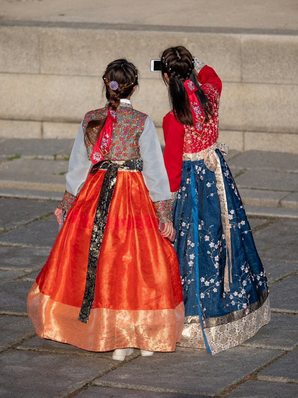 two young girls dressed in colorful dresses standing next to each other