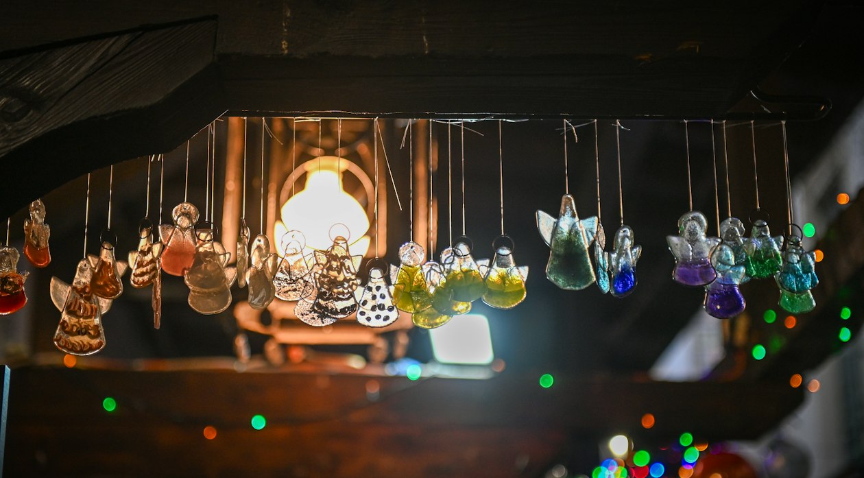 Anges de Noël en verre suspendus sous une lampe dans une petite boutique
