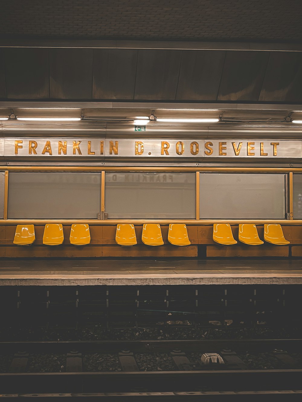 a row of yellow chairs sitting in front of a train station