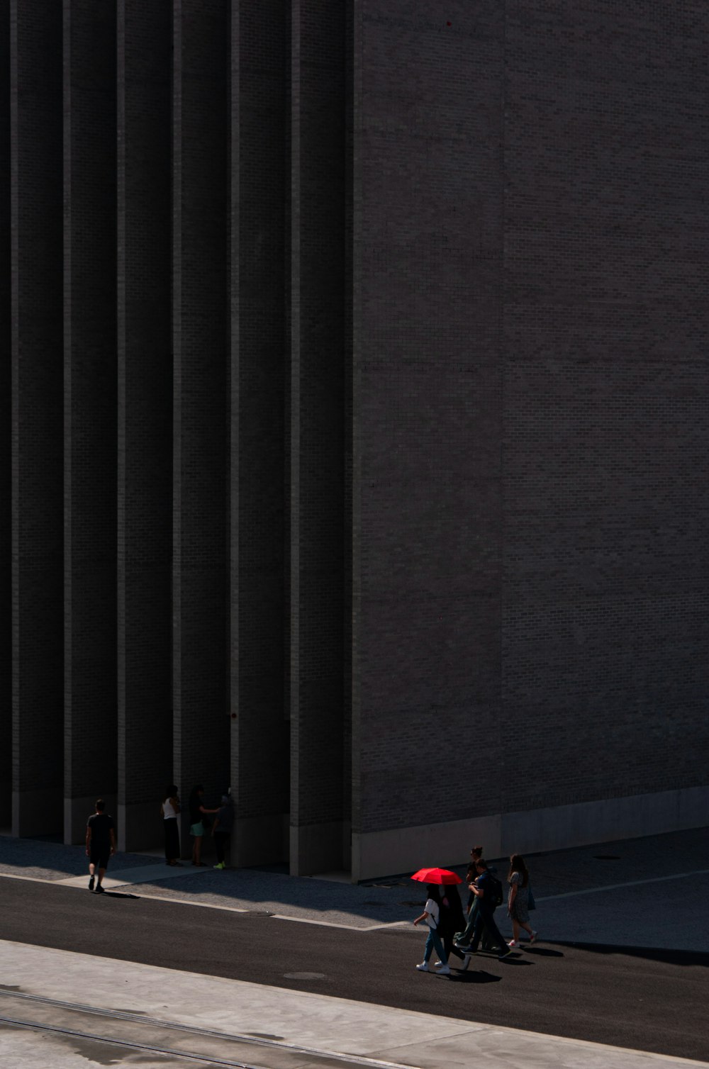 un gruppo di persone che camminano lungo una strada accanto a un edificio alto