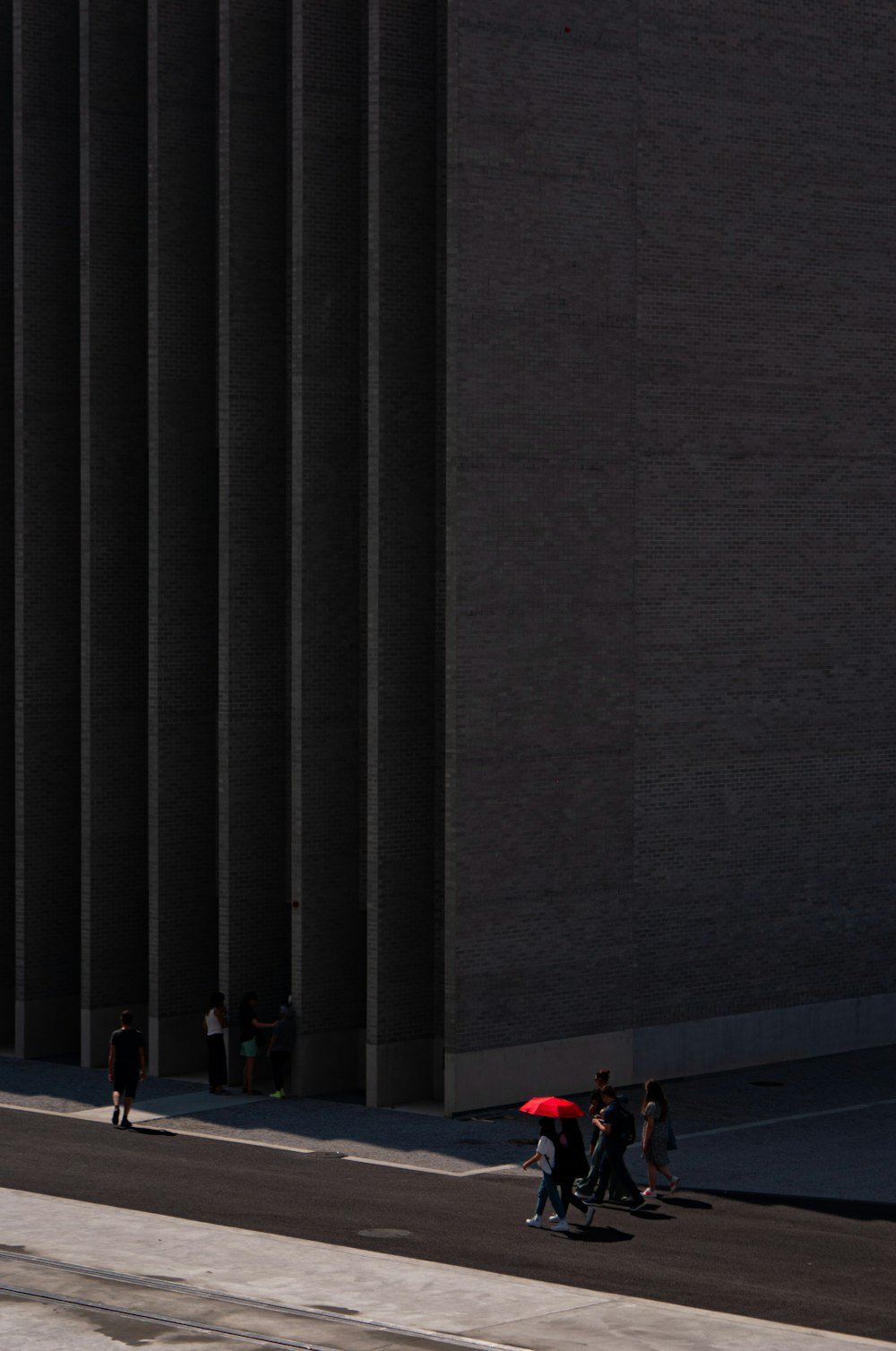 a group of people walking down a street next to a tall building