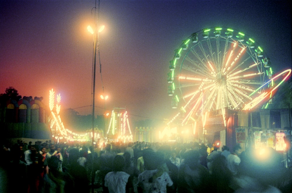 a carnival at night with a ferris wheel in the background